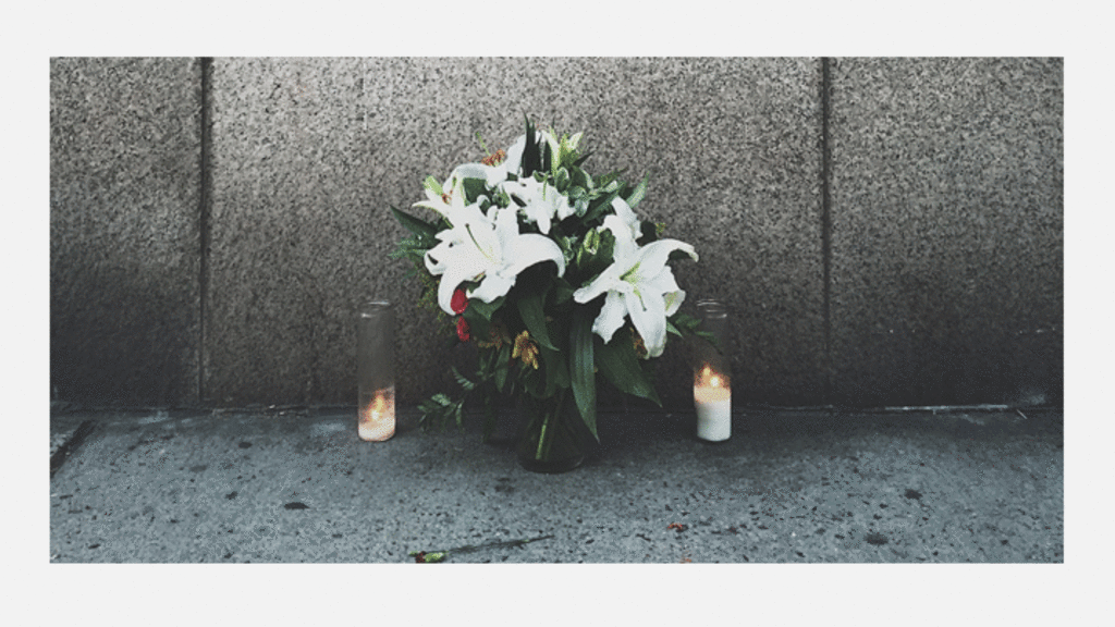 Modern photo of memorial flowers with two candles lit on either side. 