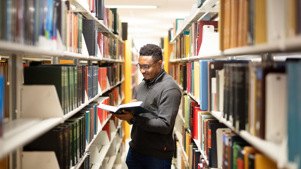 Student in the Law Library stacks with a book